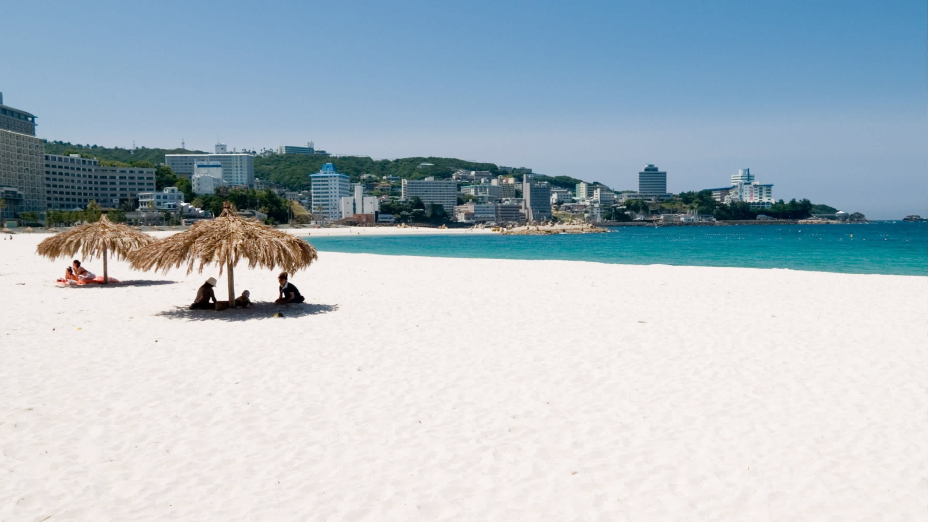 Personnes sous un parasol sur une plage d'un blanc éclatant à Shirahama au Japon