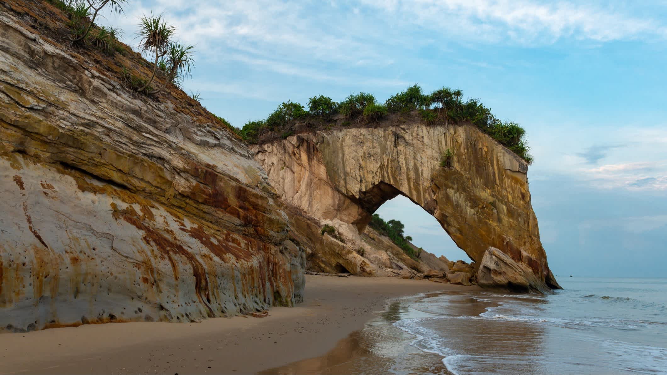 Klippen am natürlichen Sandstrand Bakam Beach, Sarawak, Malaysia mit Blick auf einen imposanten Felsbogen.