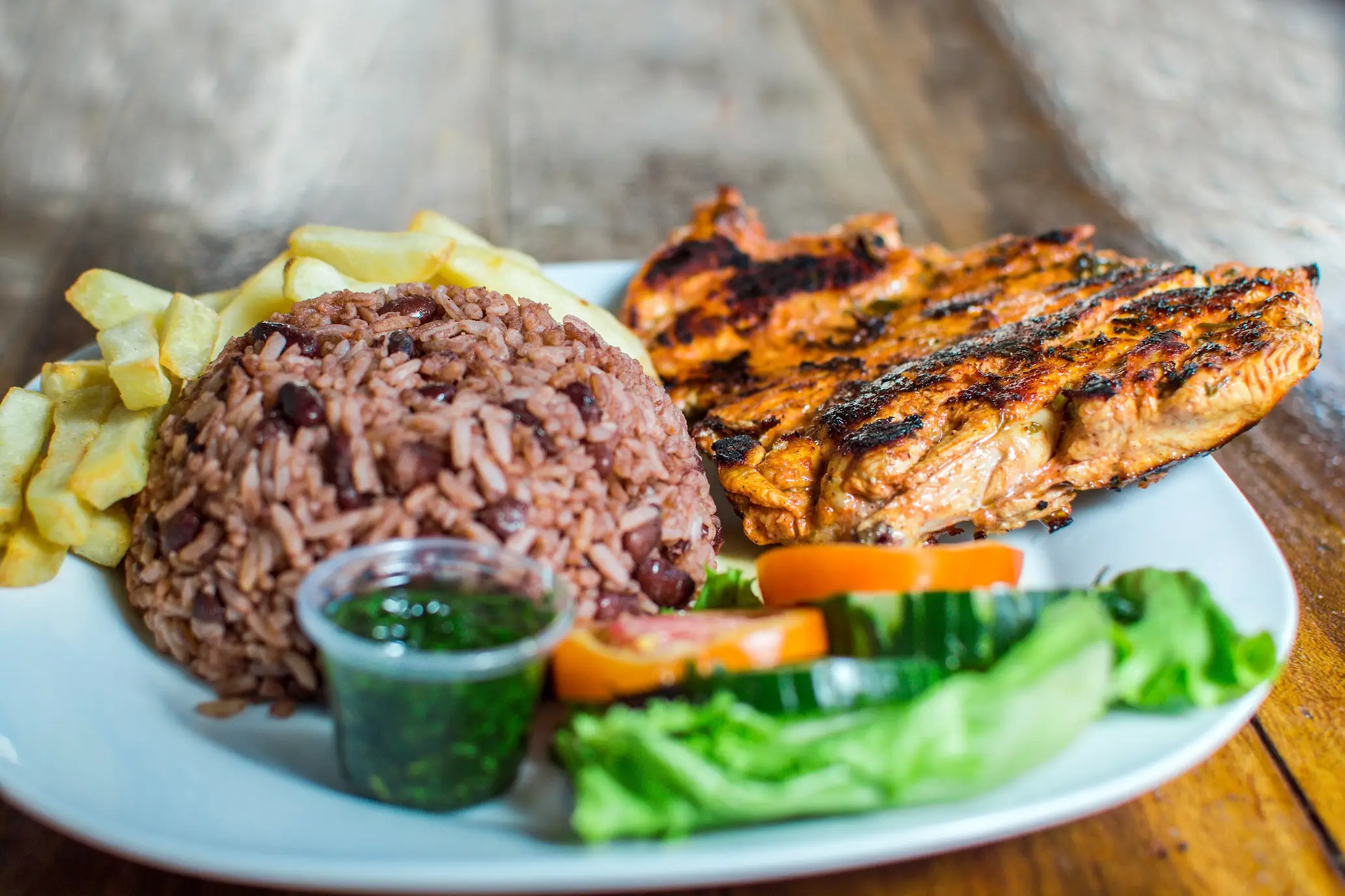 Costaricanisches Essen, Gallo Pinto Gallo Pinto Teller mit gebratenem Huhn und Reis serviert auf Holzhintergrund