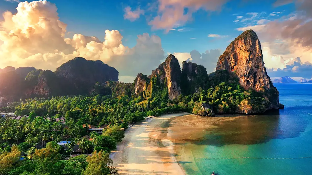 Strand mit Klippen und Palmen bei Sonnenuntergang. Railay Beach, Krabi, Thailand.