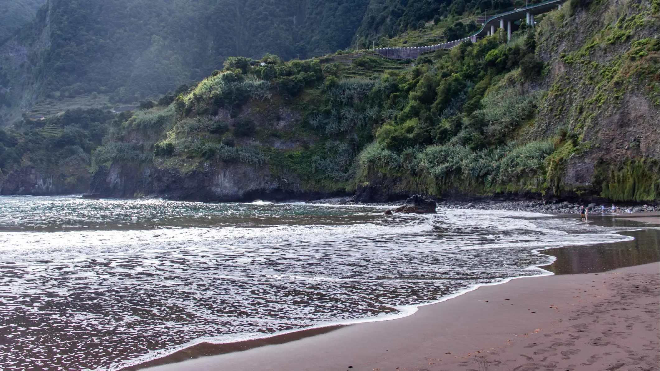 Die Küstenlandschaft mit Bridal Veil Falls, Porto Moniz, Seixal, Madeira, Portugal mit Nebel in den Bergen.