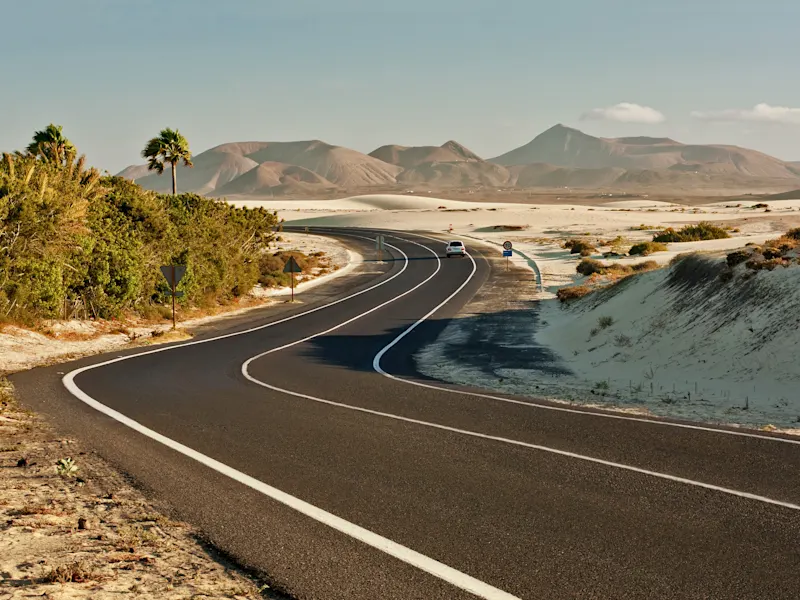 Straße durch Wüstenlandschaft mit Bergen. Corralejo, Fuerteventura, Kanarische Inseln, Spanien.