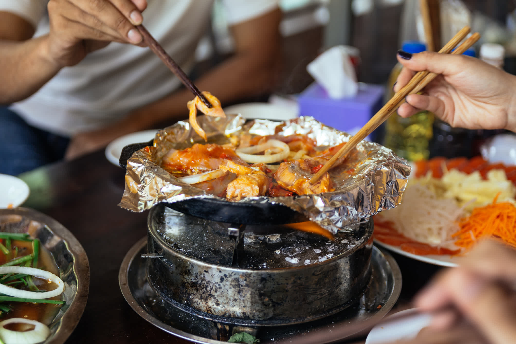 Grillen Lachs und Zwiebeln auf Folie über heiße Pfanne im Restaurant in Sa Pa, Vietnam