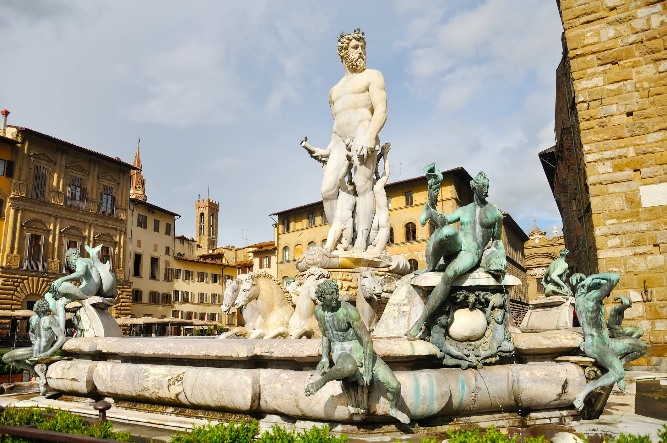 Piazza della Signoria Der Neptunbrunnen in Florenz, Italien, mit einer großen Marmorstatue des Neptun, umgeben von Bronzefiguren und Meerestieren, auf einem historischen Platz mit alten Gebäuden im Hintergrund.