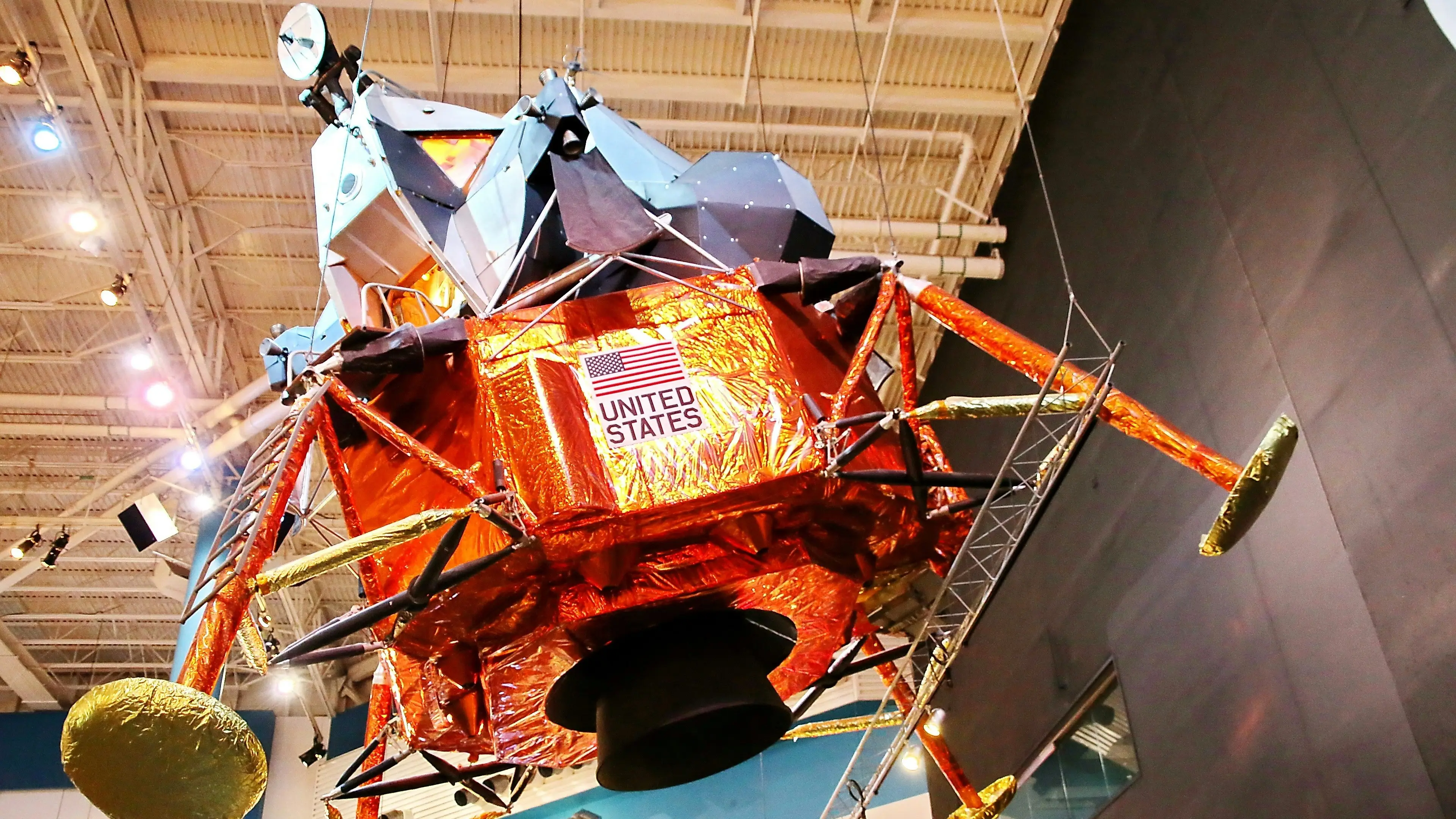 Module lunaire Apollo avec revêtement doré-orange portant l'inscription "UNITED STATES", exposé dans un musée spatial.