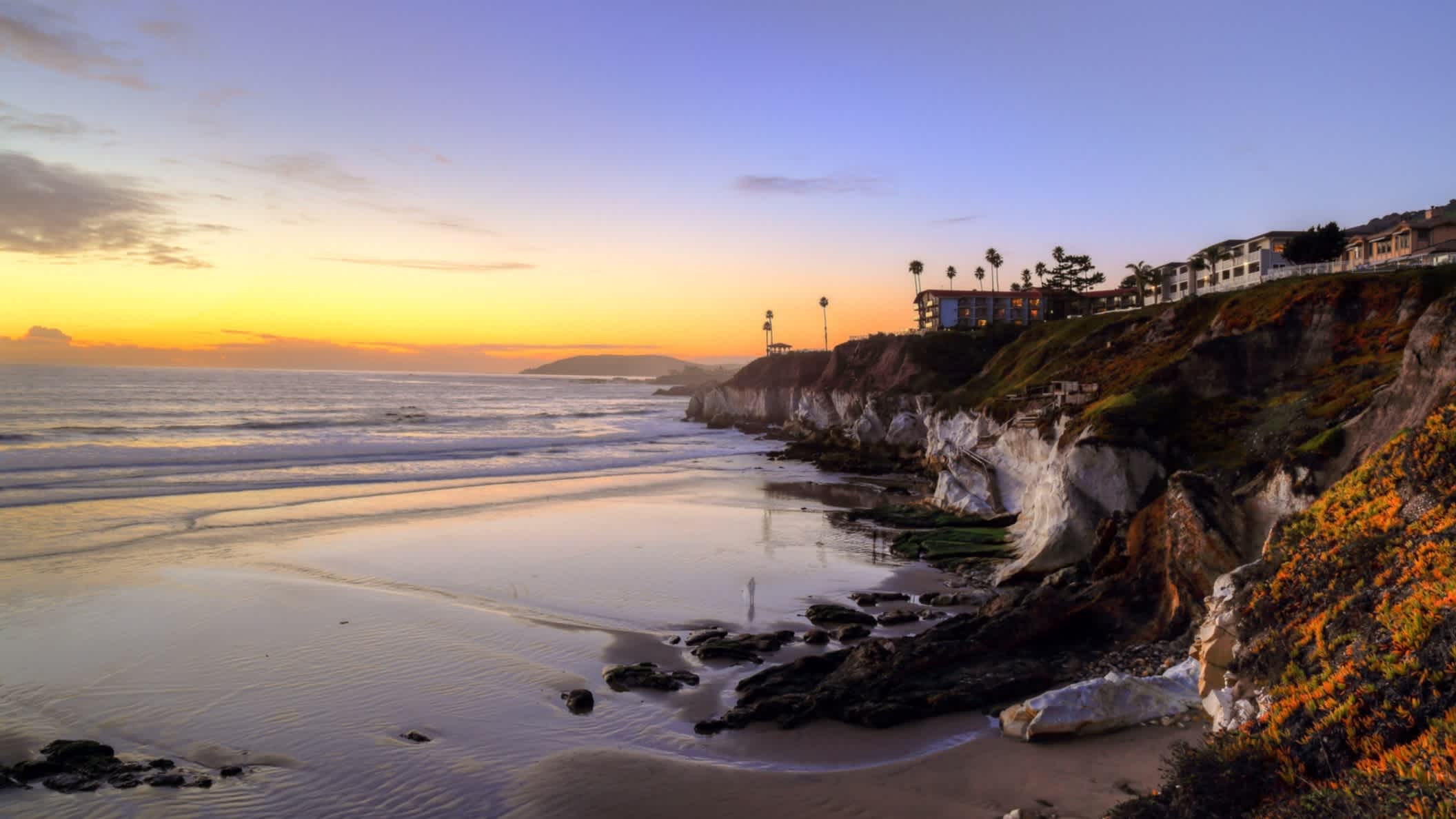 Der Strand Pismo State Beach, Pismo Beach, Kalifornien, USA bei herrlichem Abendrot und mit Blick auf das Meer sowie entlang der bewohnten Steilküste.