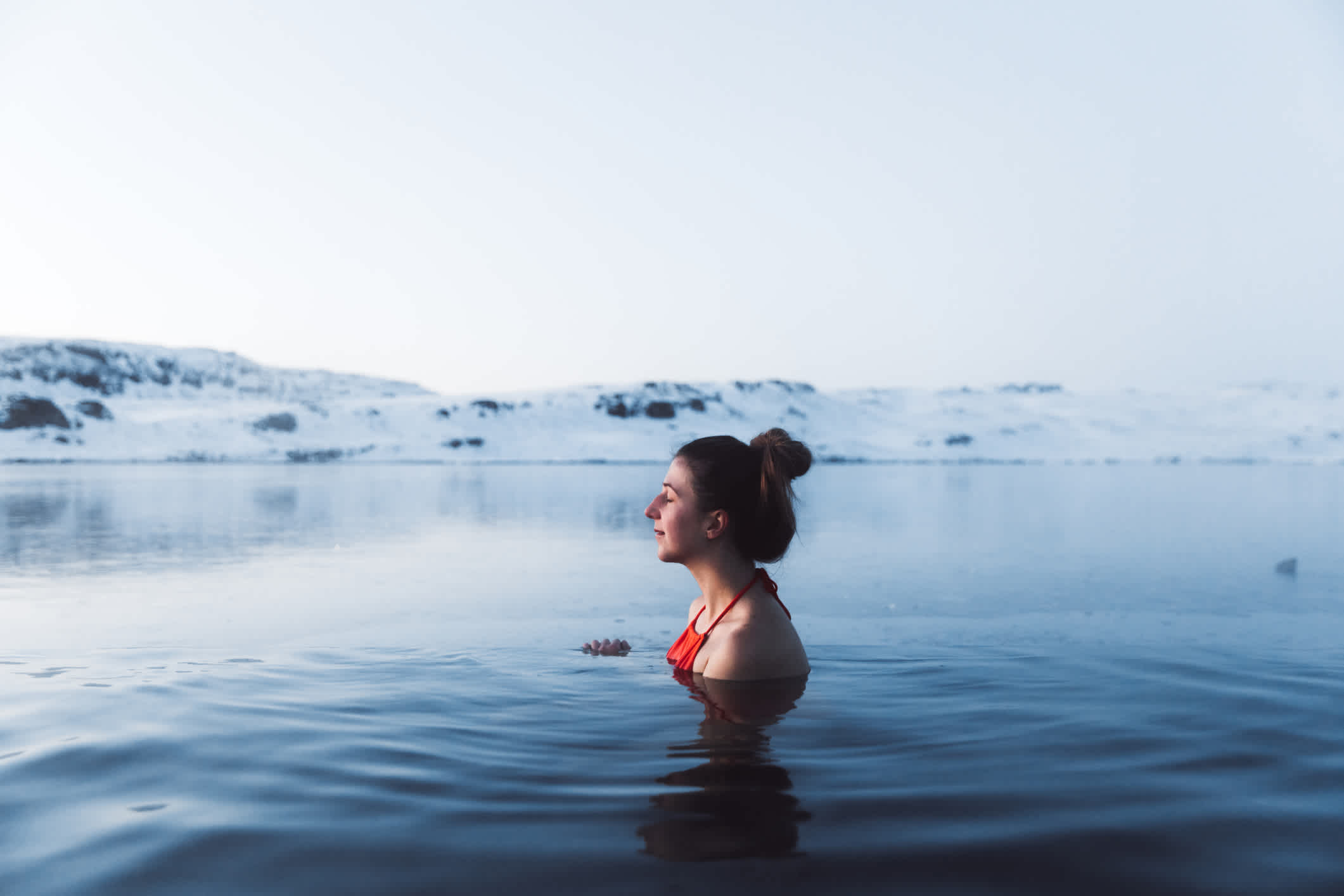 Femme dans une piscine thermale avec vue sur de magnifiques montagnes enneigées en Islande.