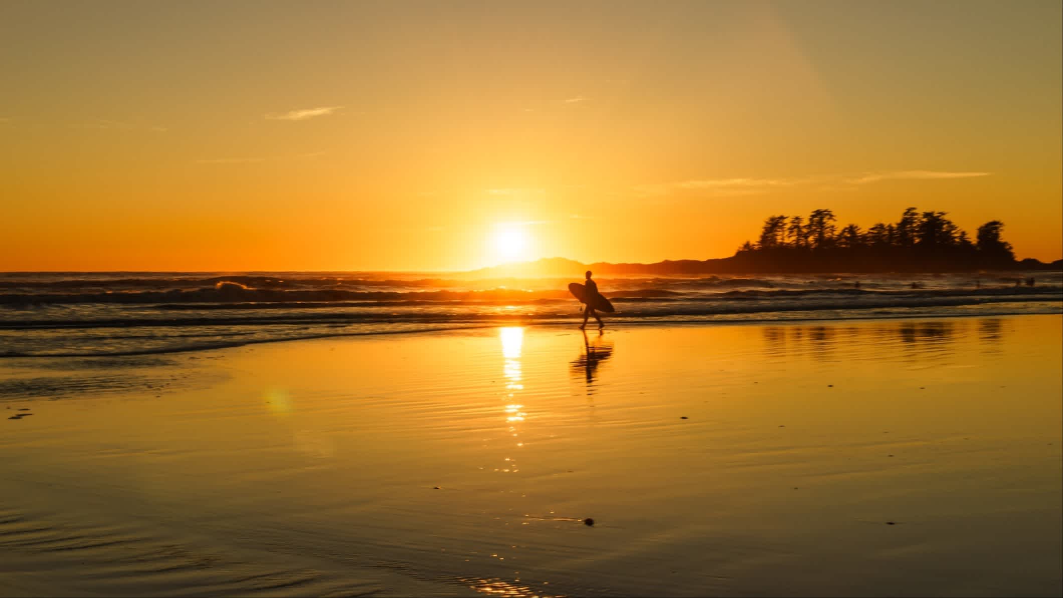 Surfer am Strand Chesterman Beach in der Region Tofino, Kanada bei Sonnenuntergang.