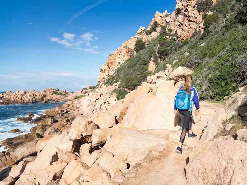 Italien, Sardinien, Santa Teresa Gallura Frau wandert entlang felsiger Küste. Santa Teresa Gallura, Sardinien, Italien.