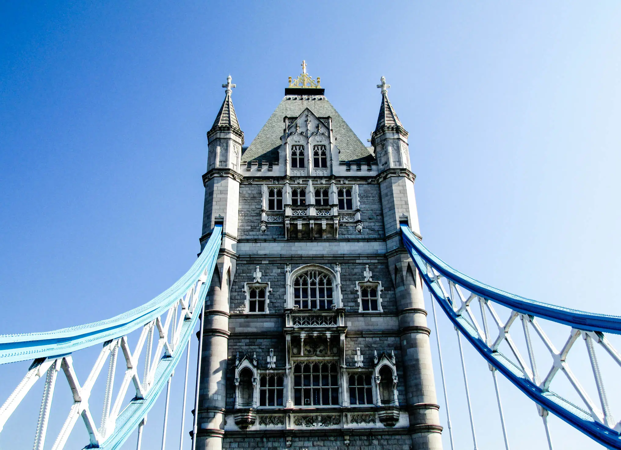Nahaufnahme eines Turms der Tower Bridge in London mit gotischer Architektur gegen blauen Himmel.