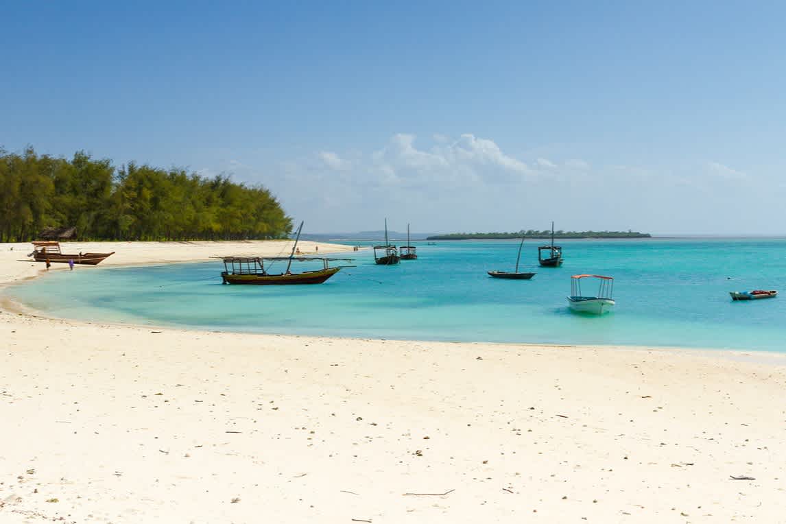 Holzboote im kristallklaren Wasser an einem Strand in Sansibar