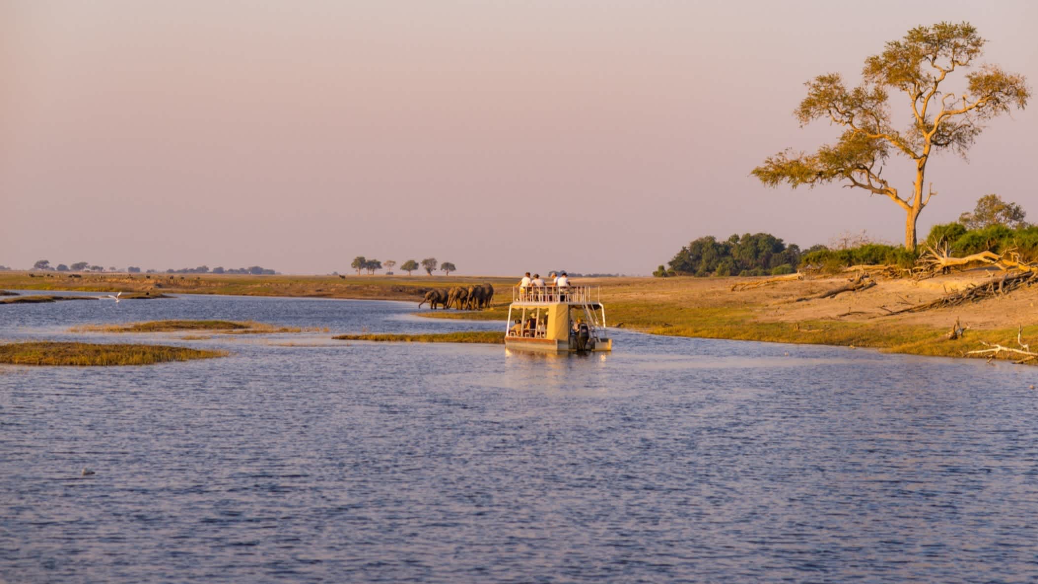 Der bezaubernde Caprivistreifen mit einem Safari-Auto im Wasser im Norden Namibias bei Sonnenuntergangsstimmung.