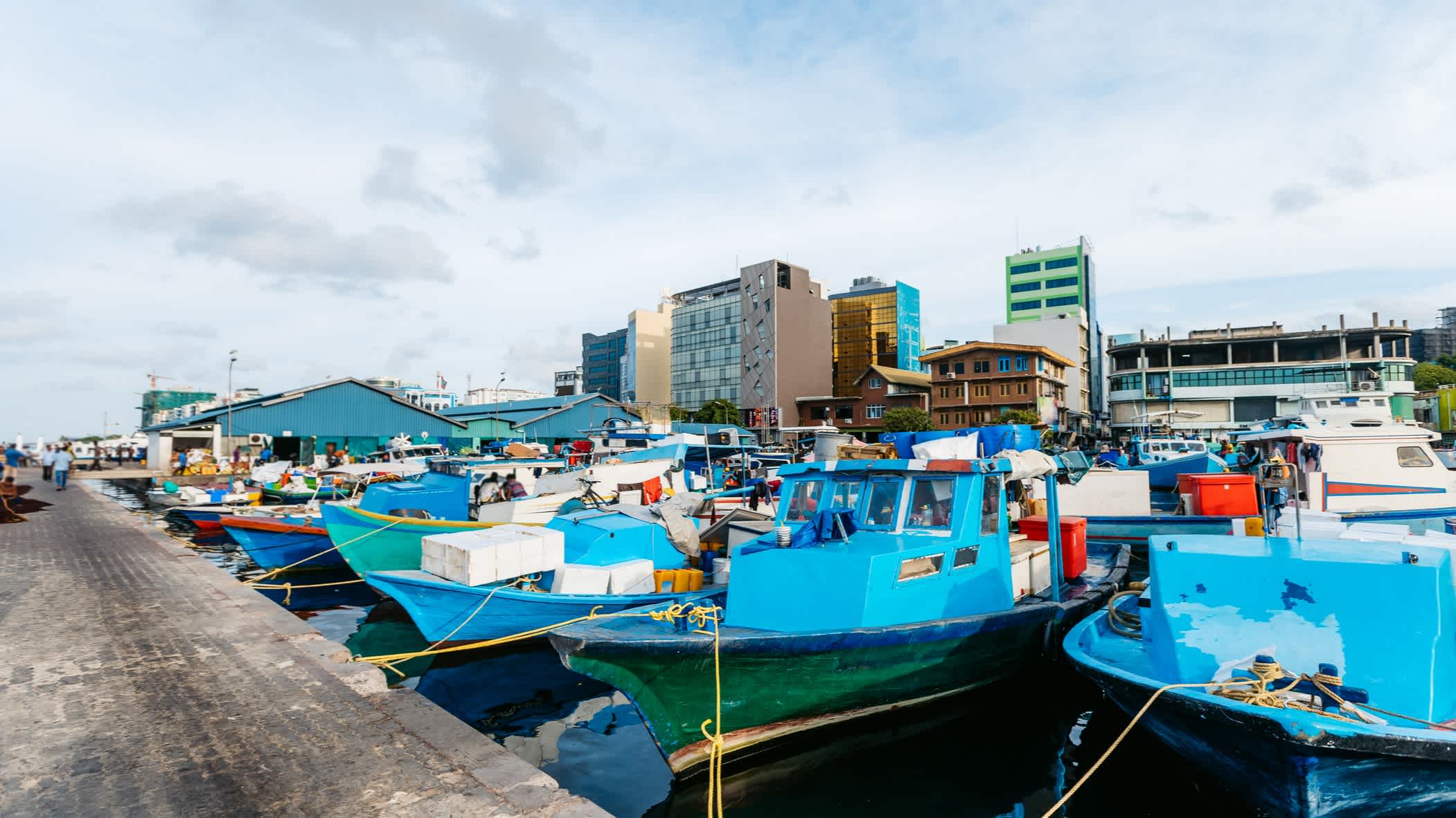 Kleine blaue Fischerboote liegen im Hafen von Malé