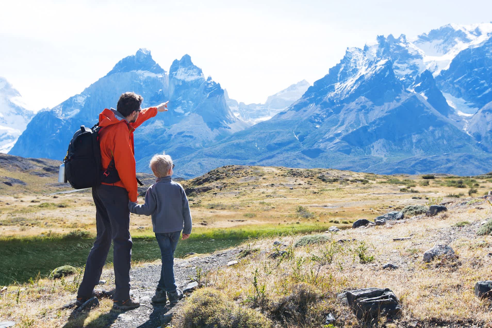 Vater und Sohn genießen die Aussicht auf die Cuernos del Paine in den Anden.
