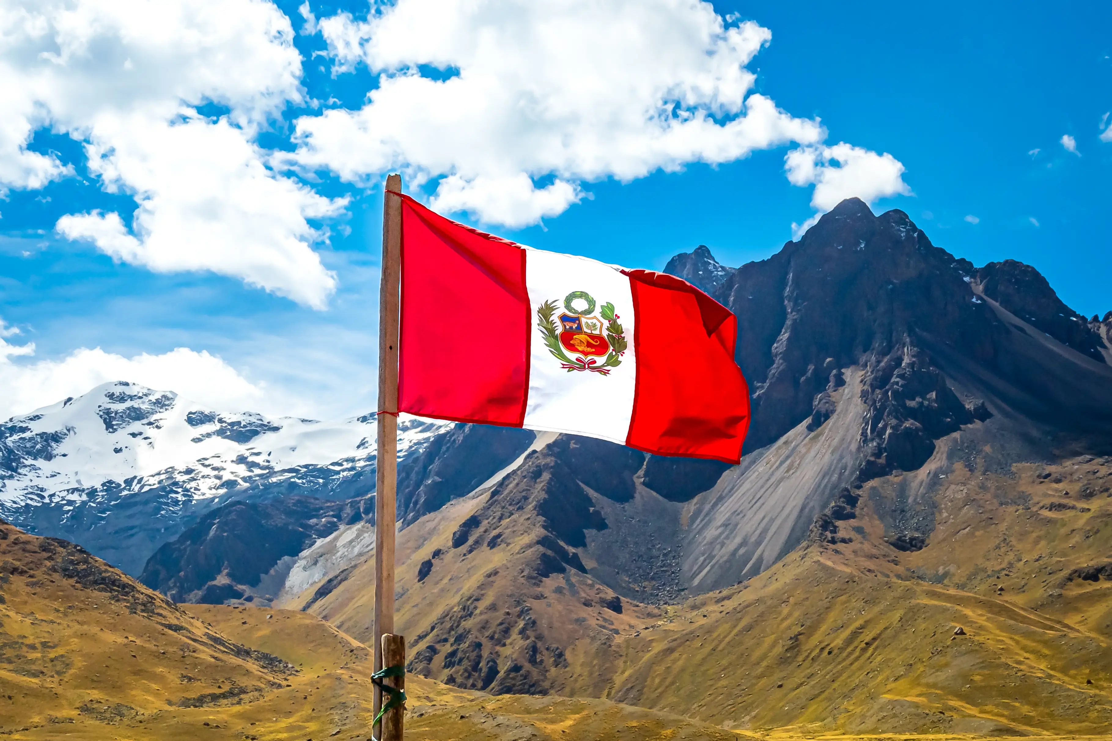 Le drapeau péruvien, avec en arrière-plan la chaîne de montagnes de La Raya, avec le sommet enneigé du Chimboya et une vue imprenable sur les Andes.