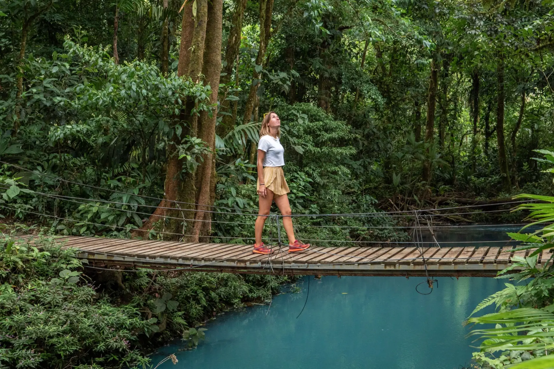 Costa Rica, Canopy-Tour Junge Frau wandert auf der Brücke über türkisfarbene Lagune in Costa Rica.