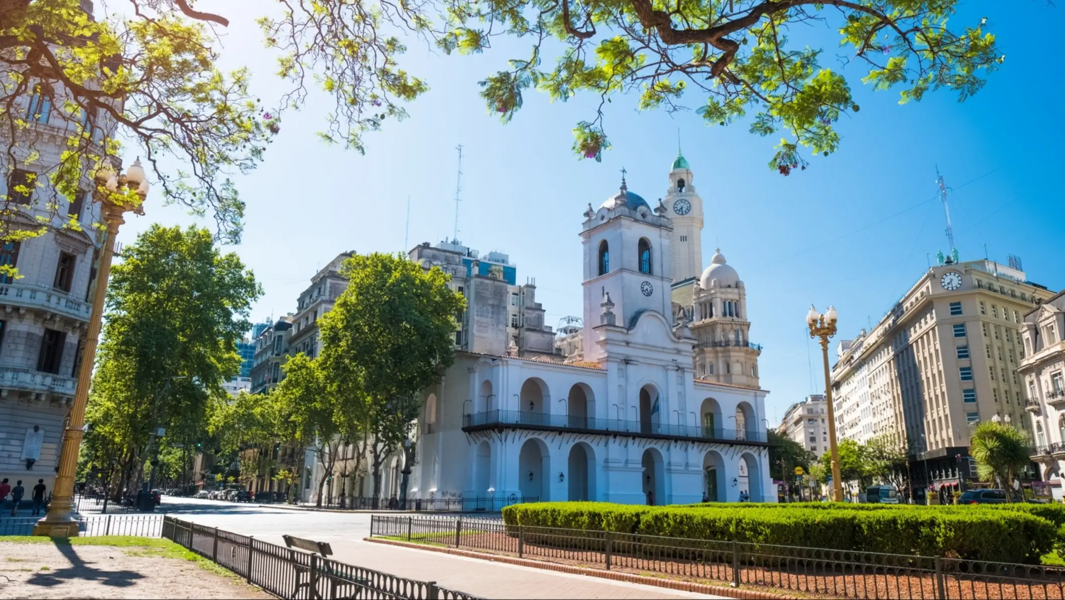 Bâtiment historique blanc avec une tour d'horloge et des arbres verts au premier plan, Buenos Aires, Argentine.