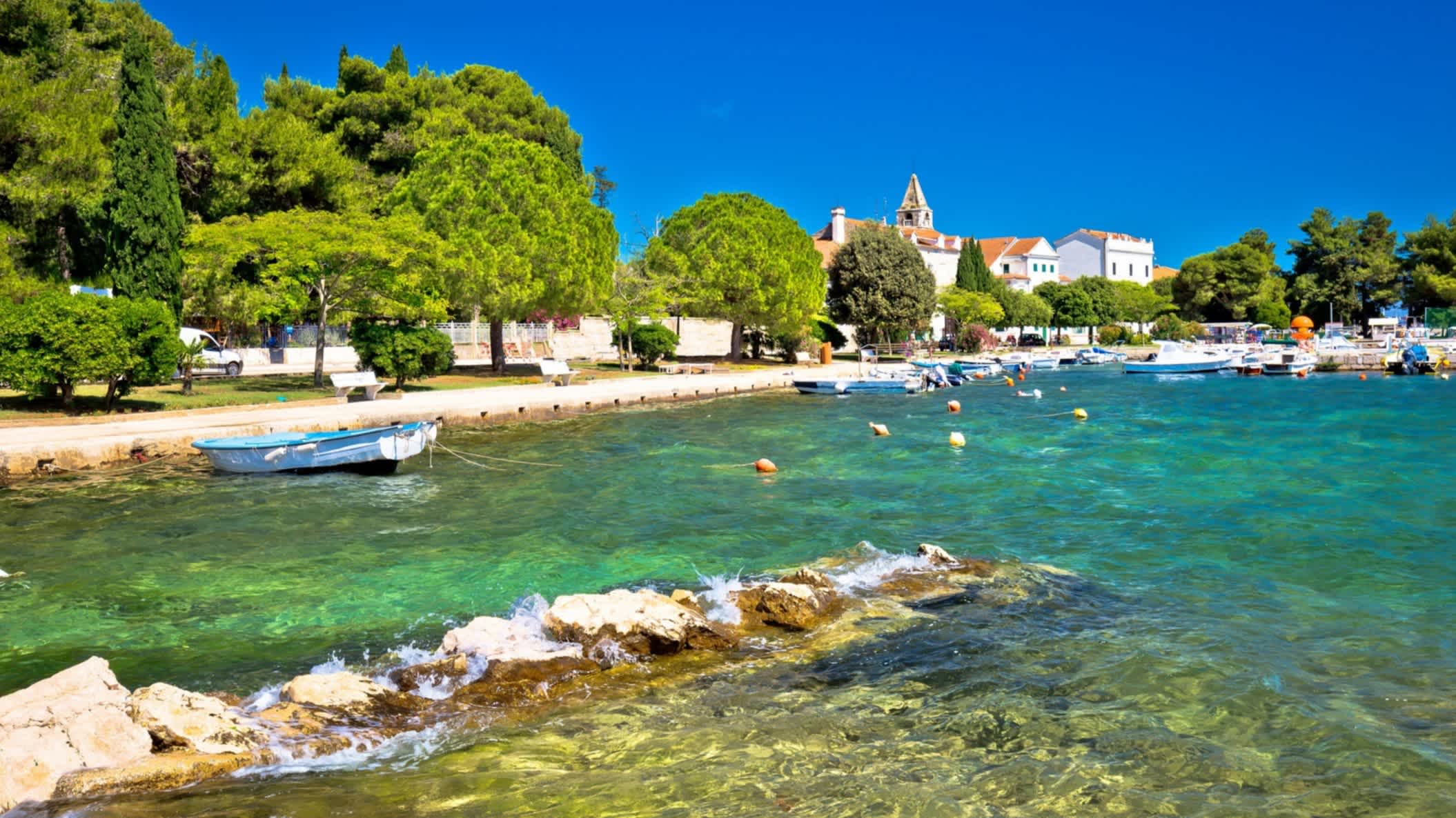 Strand von Sveti Jakov, Dubrovnik, Kroatien mit Blick auf das Wasser, die Stadt und ein Boot im Wasser.