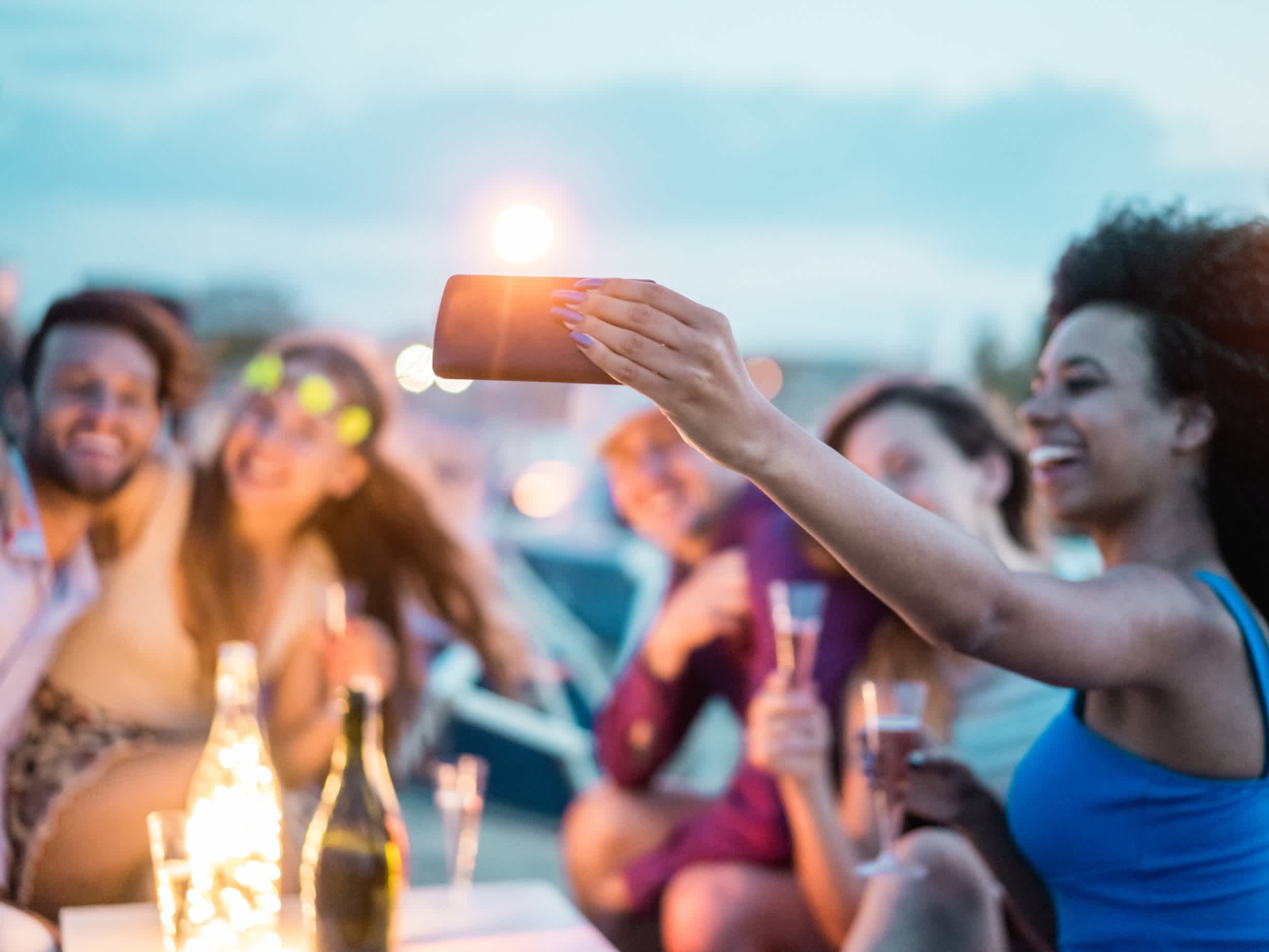Personnes faisant un selfie avec un smartphone lors d'une fête de plein air sur une plage