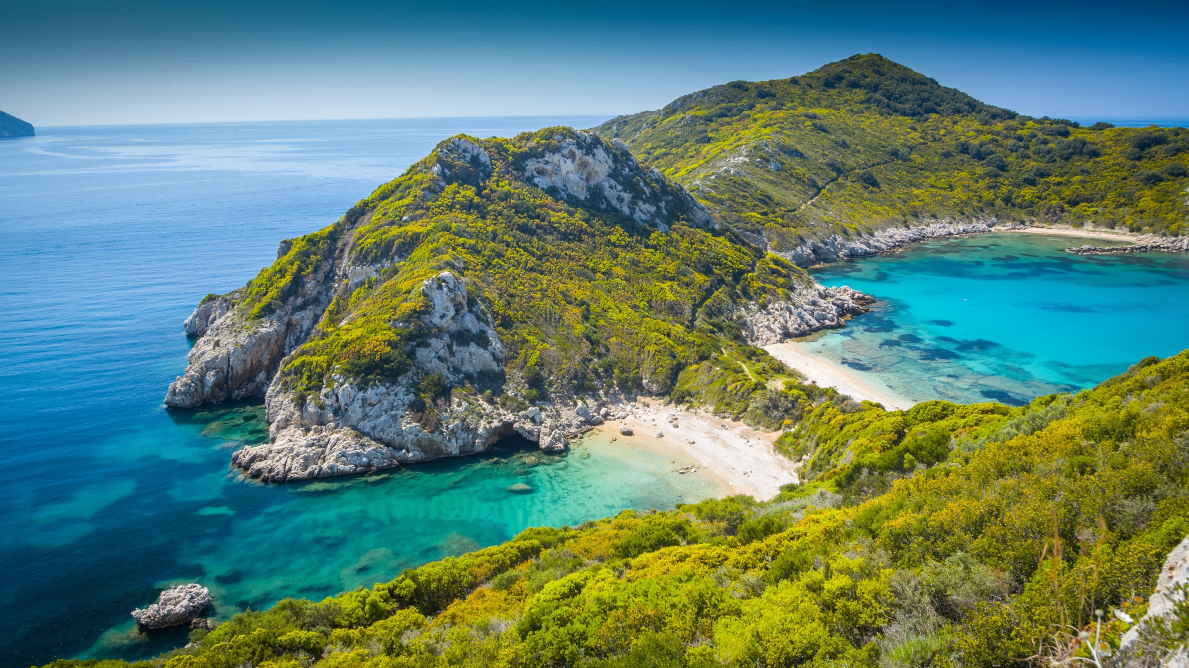 Der Strand Porto Timoni Beach, Korfu, Ionische Inseln, Griechenland mit Blick von oben auf grüne Hügel, das Riff und bei Sonne.
