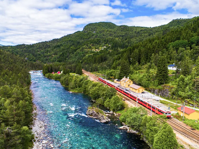 Ligne de train au bord d'une rivière, entourée de forêts. Flåm, Sogn og Fjordane, Norvège.
