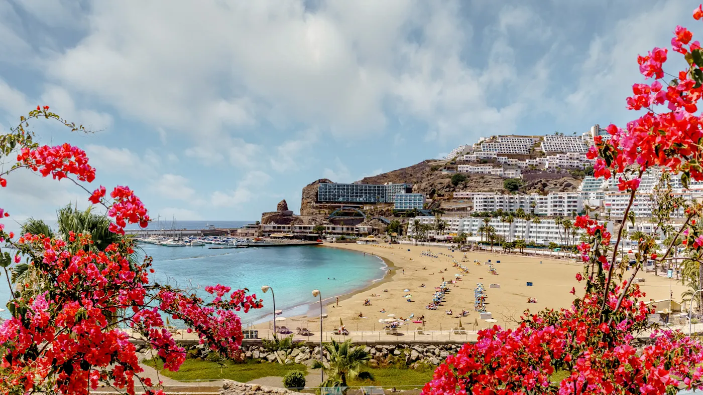 Spanien, Gran Canaria, Puerto Rico Strand mit Blumen, blauen Wasser und Hotels. Puerto Rico, Gran Canaria, Spanien.