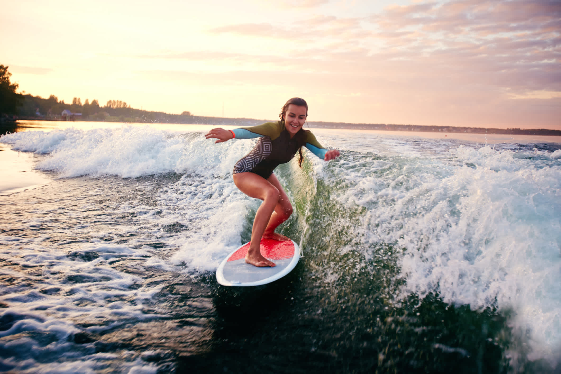 Jeune femme sur une planche de surf au coucher du soleil.
