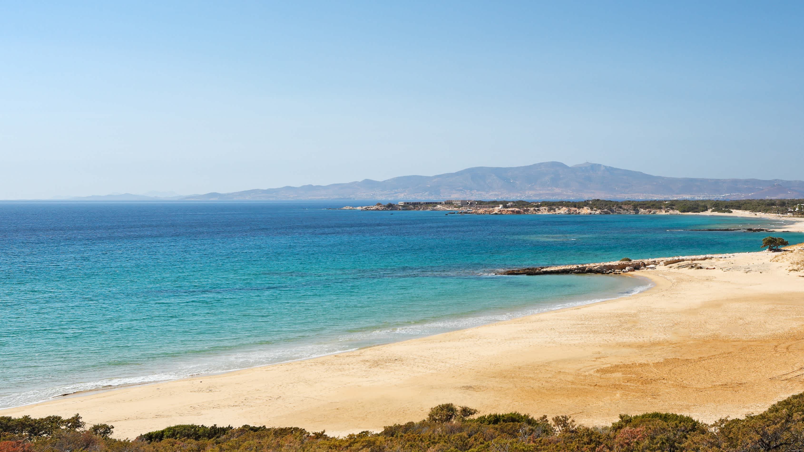 Der Sandstrand Pyrgaki auf Naxos, Griechenland, mit goldgelbem Sand und türkisblauem Meer.