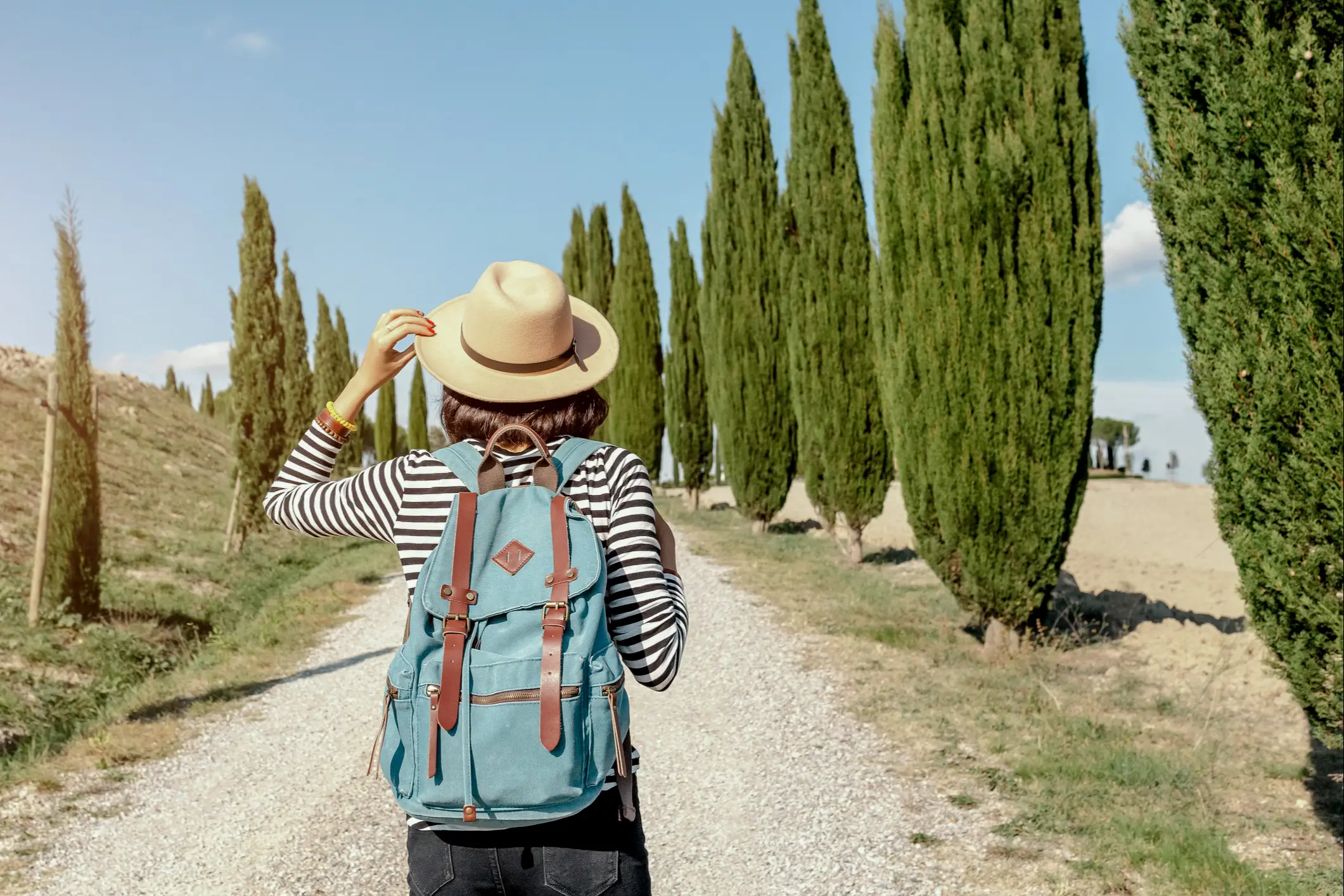 Junge Frau wandert durch eine Zypressenallee in Toskana, Italien