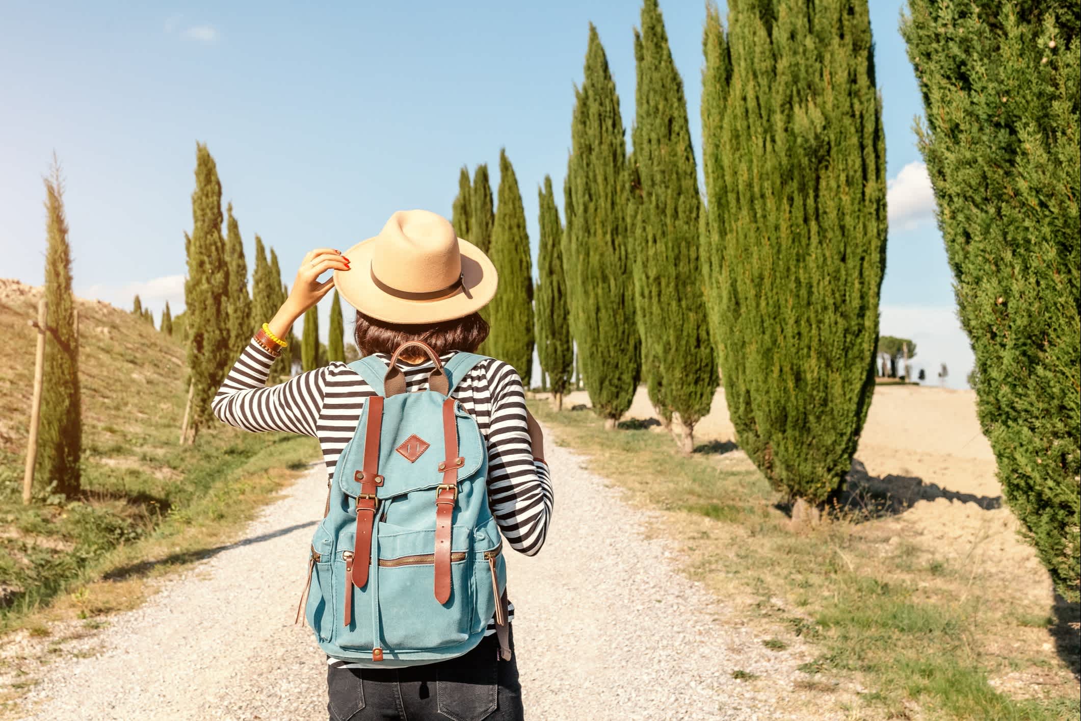 Junge Frau wandert durch eine Zypressenallee in Toskana, Italien