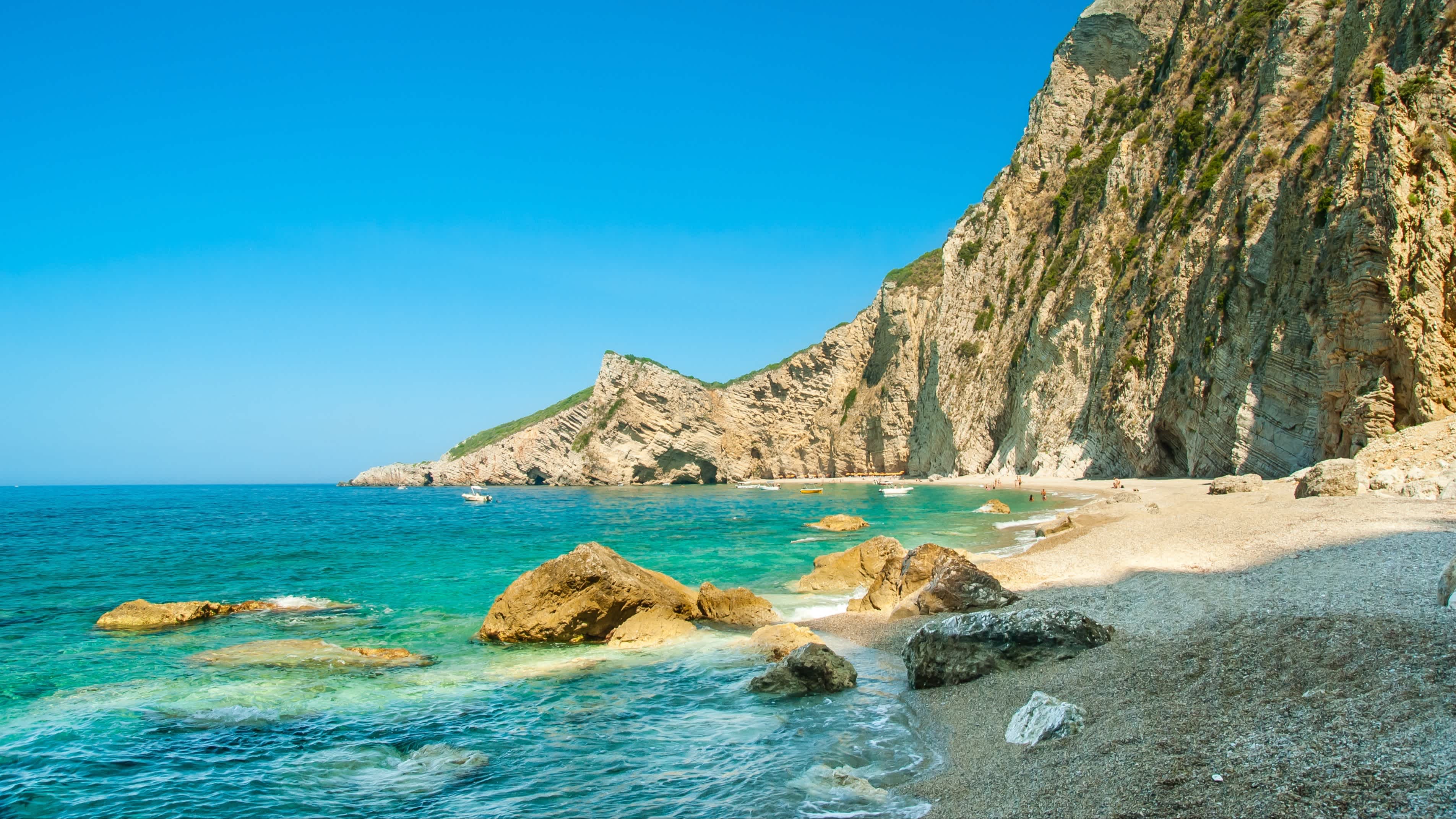 Der Paradise Beach nahe Liapades, Insel Korfu, Griechenland mit Felsenklippen im Hintergrund und bei Sonnenschein.
