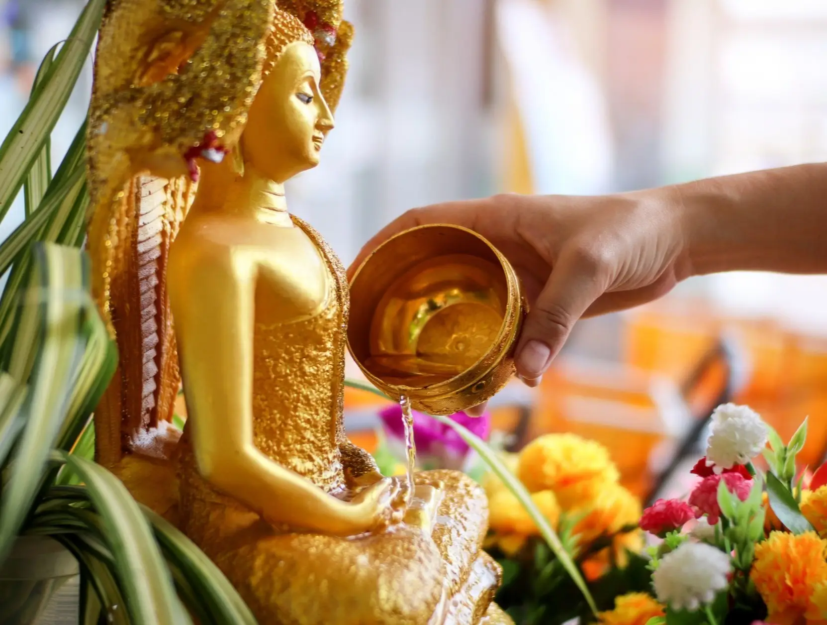 Thaïlande, Bangkok, fête de l'eau de Bouddha Main d'une femme répandant de l'eau sur une statue dorée de Bouddha lors du Songkran Festival en Thaïlande.