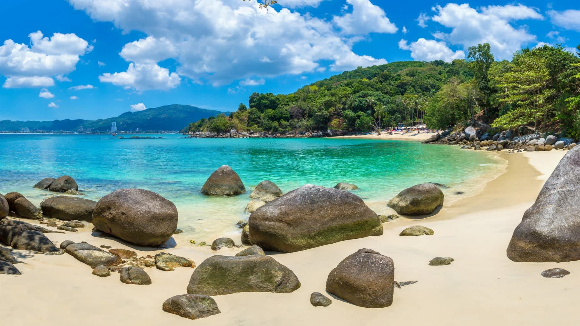 Die Paradise Beach Bucht auf Phuket mit Felsen, türkisblauem Wasser und grünen Hügeln.