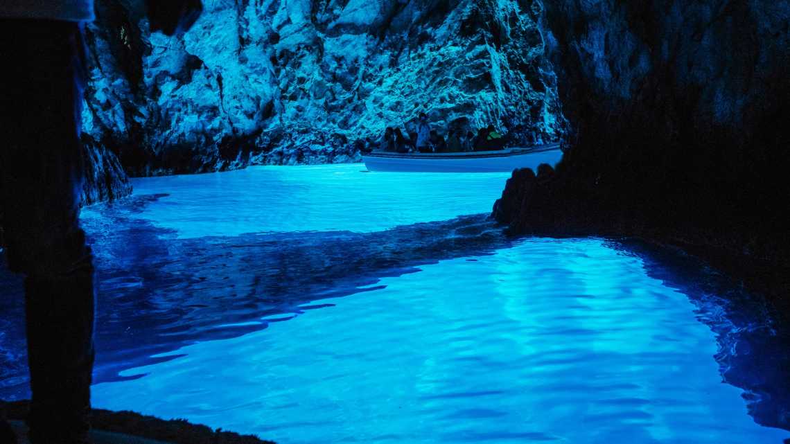 Personnes visitant la spectaculaire grotte bleue en bateau sur l'île de Bisevo, Croatie