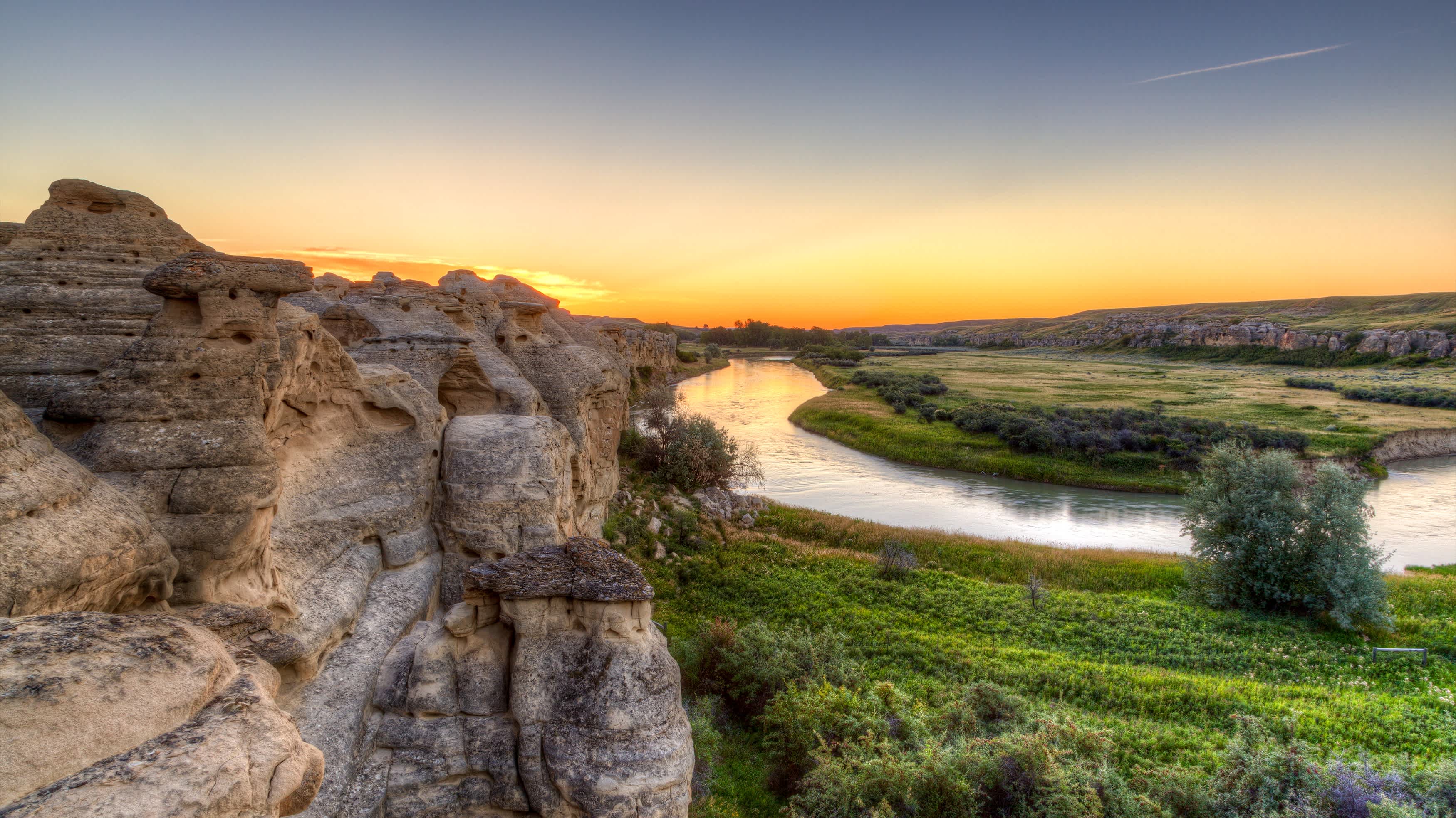 Lever de soleil doré sur les Hoodoo Badlands dans le parc provincial Writing-on-Stone en Alberta, Canada.