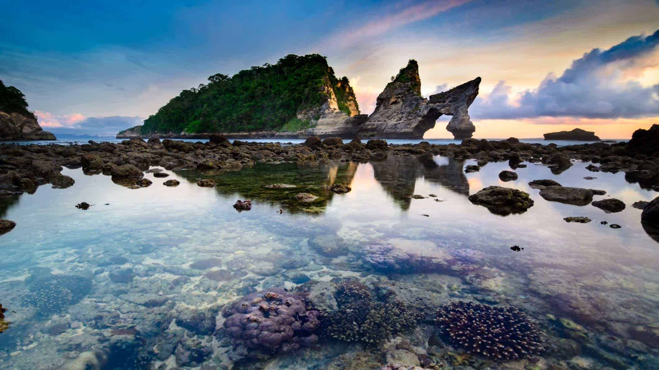 eau transparente entourée de rochers au soleil couchant sur la plage d'Atuh en Indonésie