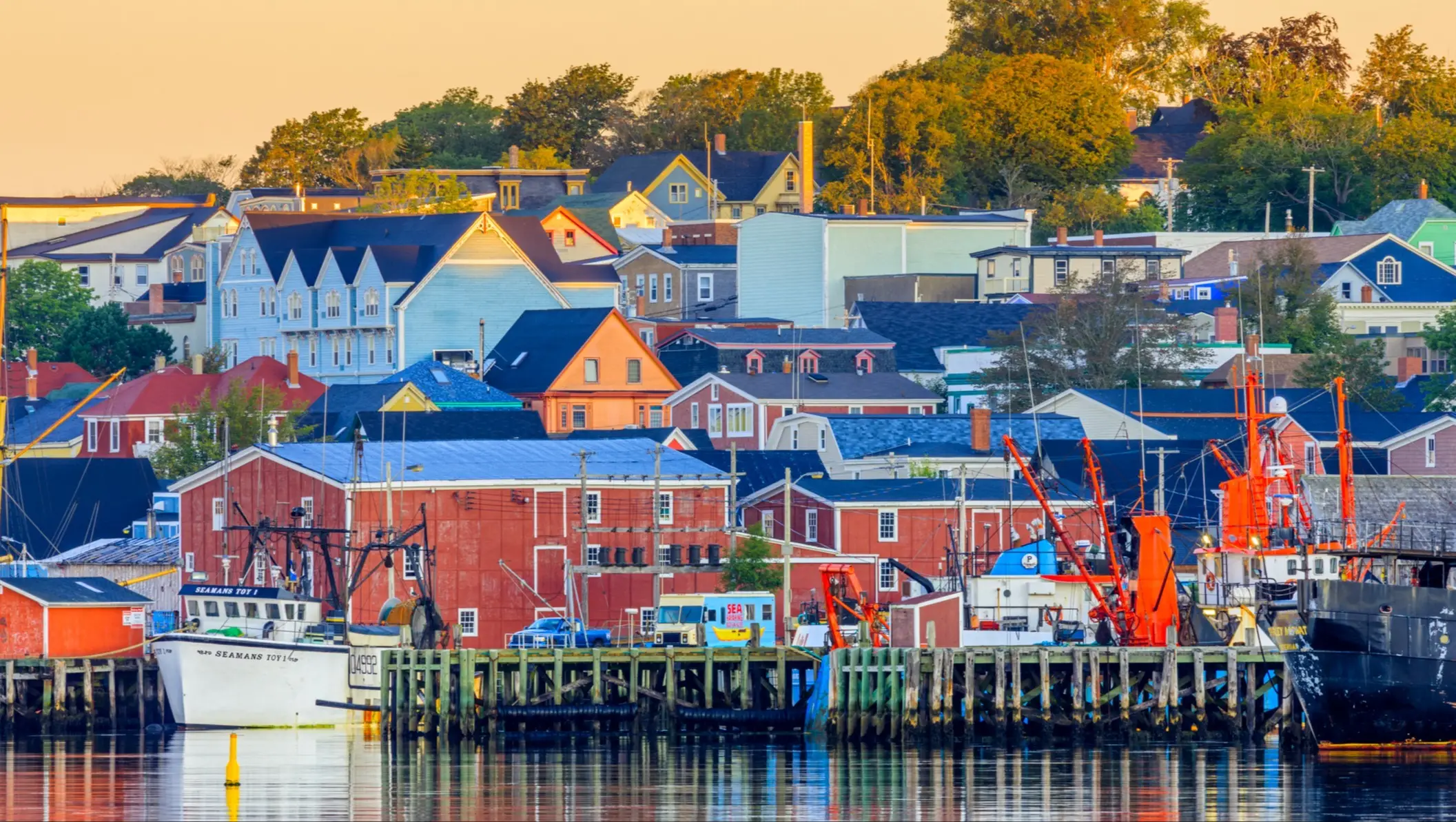 Lunenburg, Nouvelle-Écosse, Canada Des maisons en bois colorées et des bateaux de pêche se reflètent dans l'eau du port. Lunenburg, Nouvelle-Écosse, Canada.