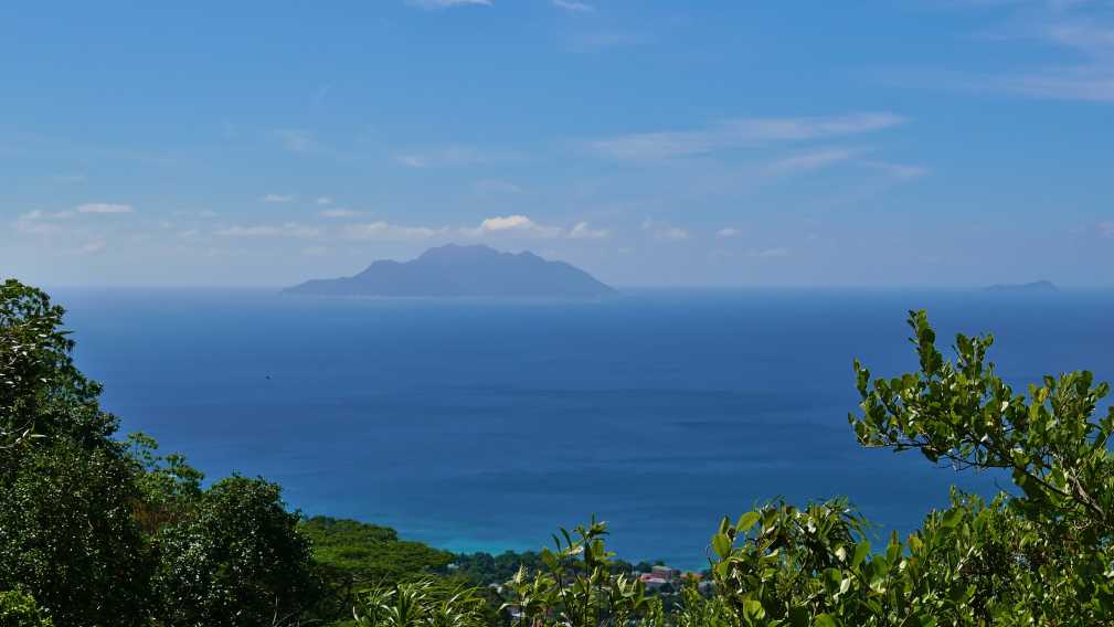 Panoramablick von Mahe, Seychellen, über die nördliche Küstenlinie mit den Silhouetten der Silhouette Island und der Ile du Nord am Horizont.