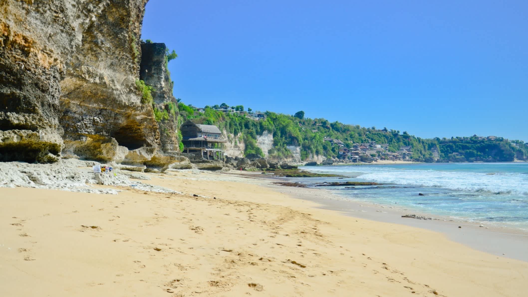 Plage bordée de rochers verdoyants à Dreamland Beach à Bali, en Indonésie.