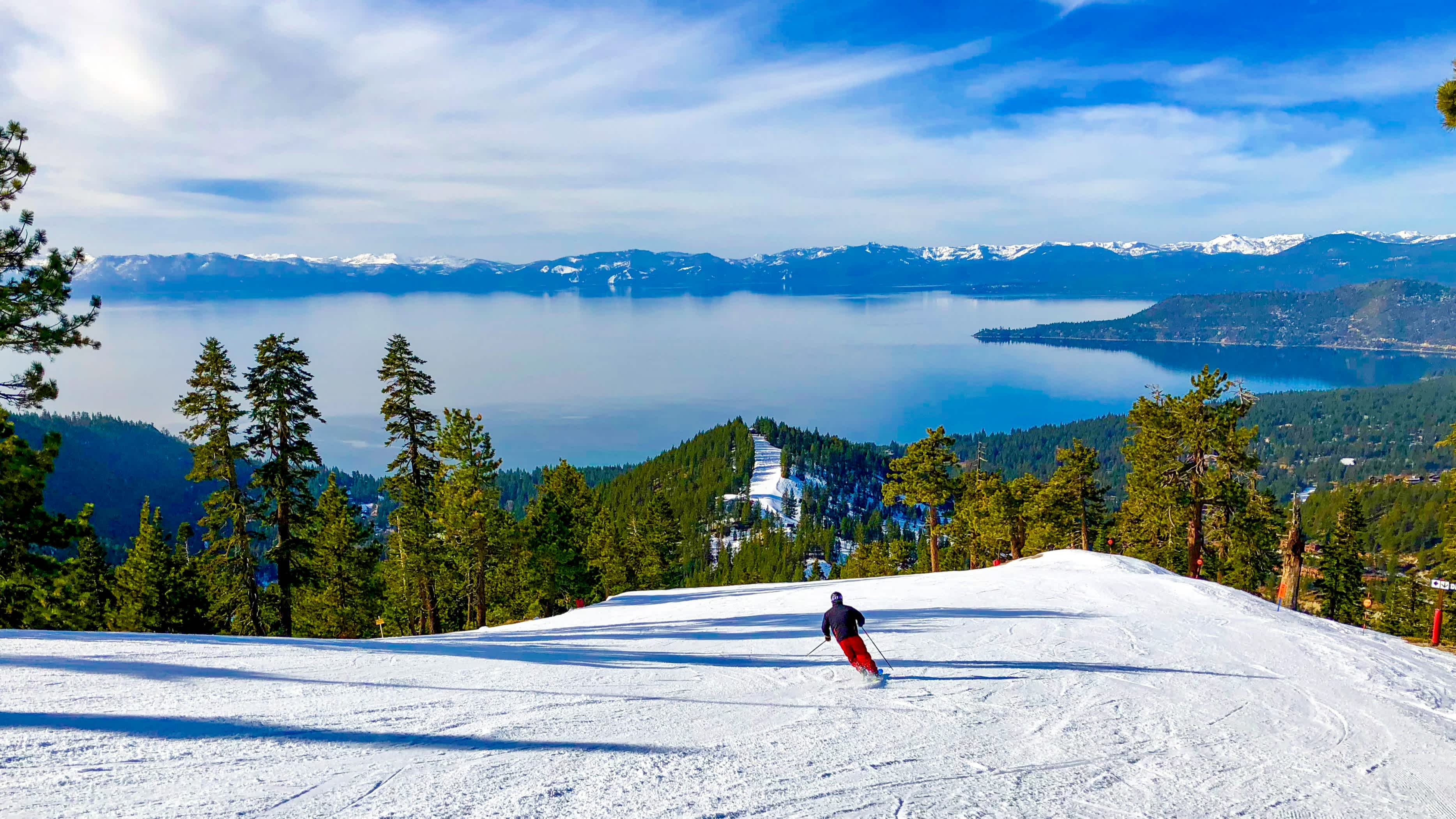 Un skieur en train de descendre une piste avec une vue panoramique sur le lac Tahoe en Californie, États-Unis