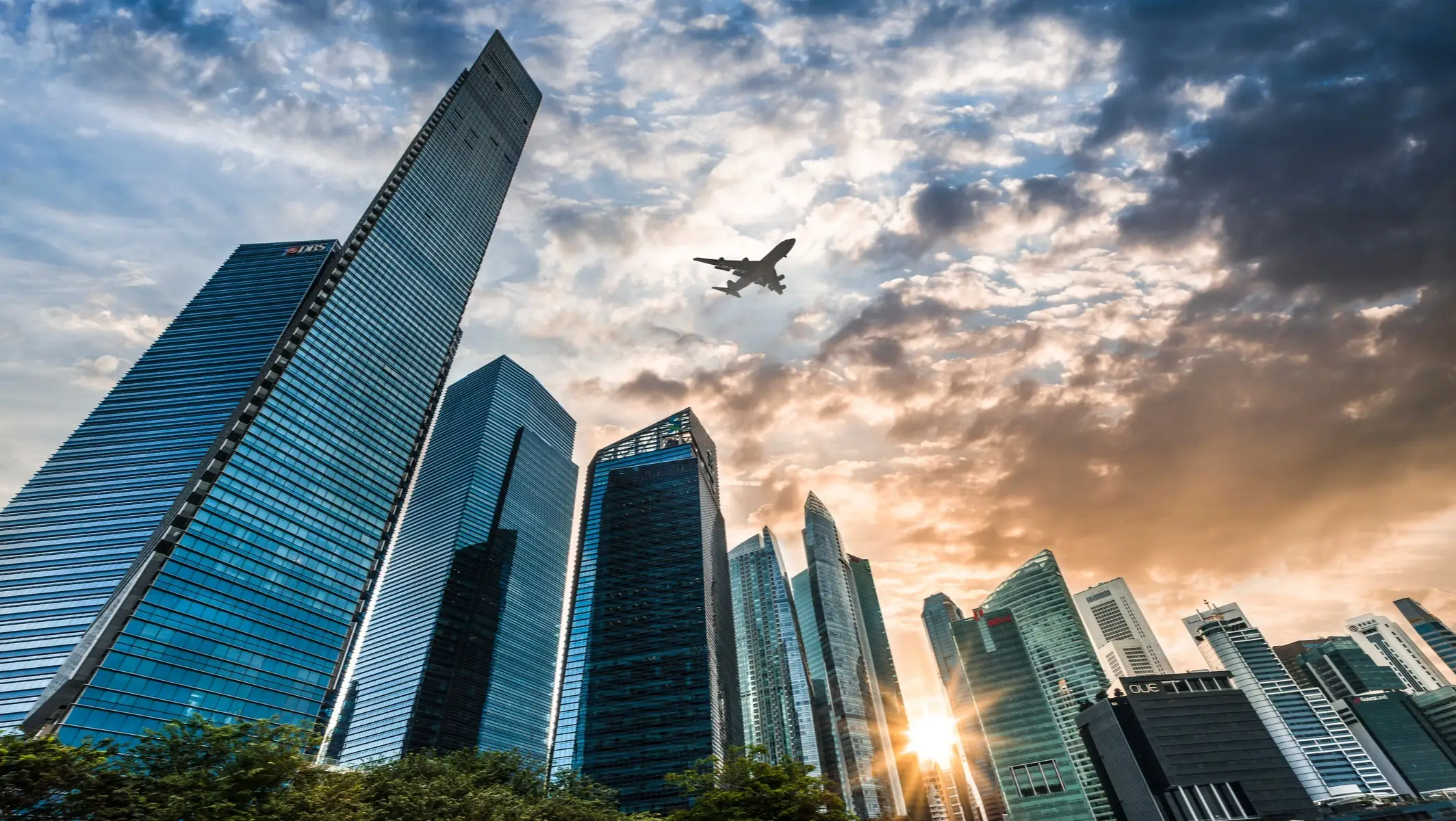 Marina Bay, Singapur Flugzeug fliegt über moderne Skyline bei Sonnenuntergang, Marina Bay, Singapur.