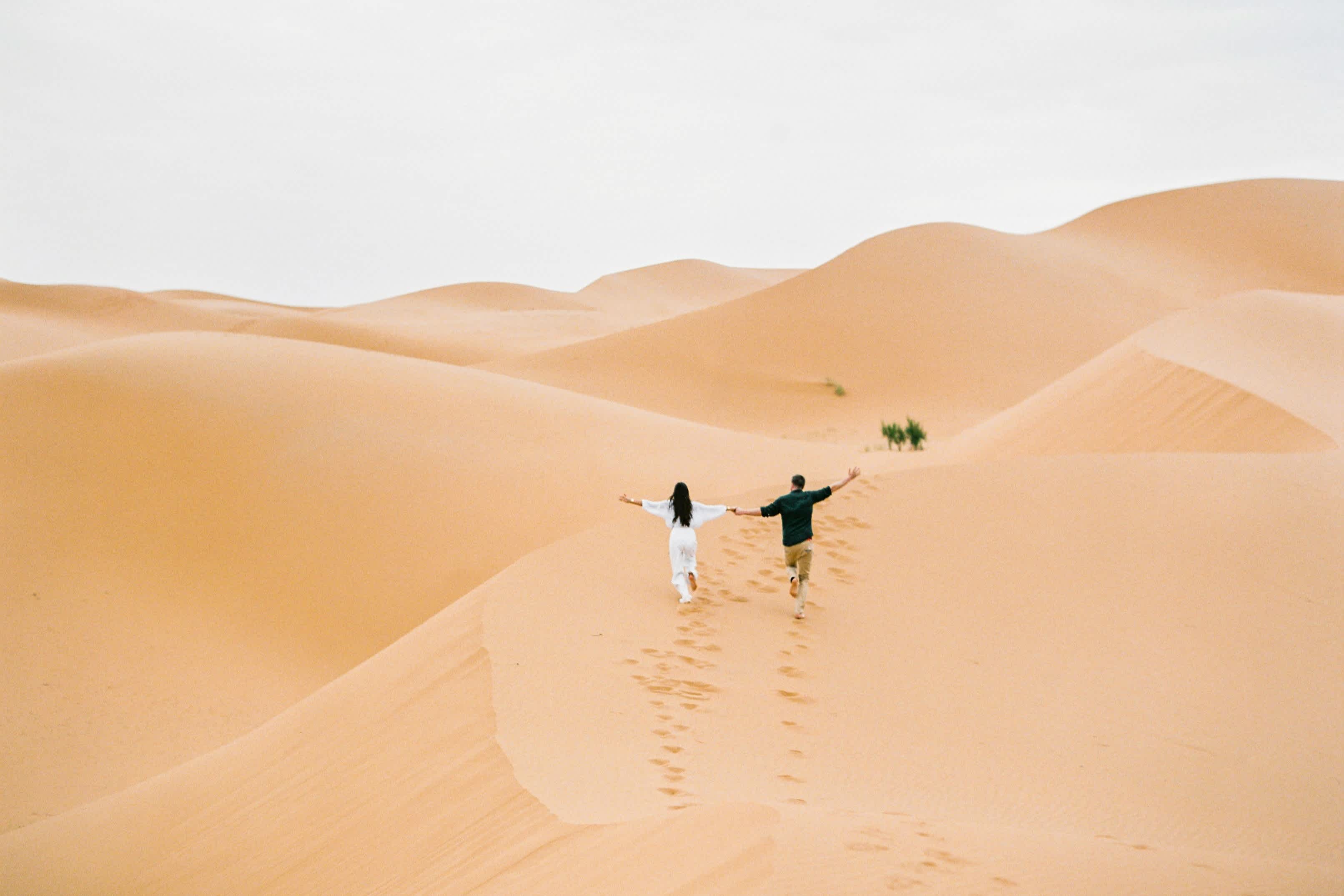 Un couple marche dans le désert en se tenant la main