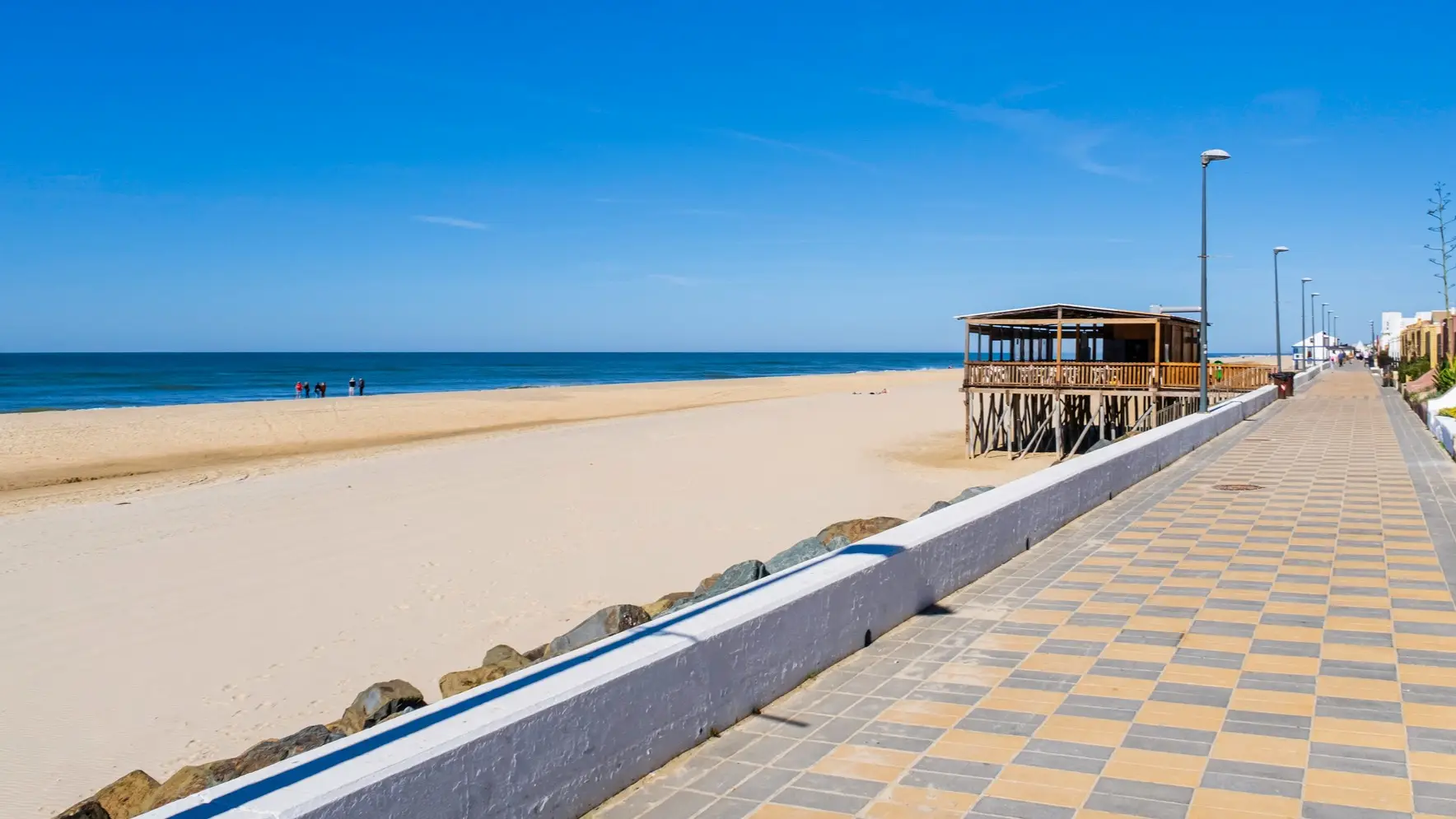Strand bei Sonnenuntergang mit Leuchtturm im Hintergrund