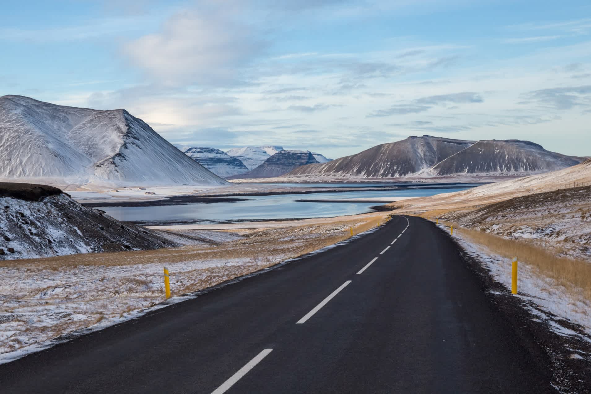Eine Landstraße in einer verschneiten Berglandschaft in Snaefellsnes, Island