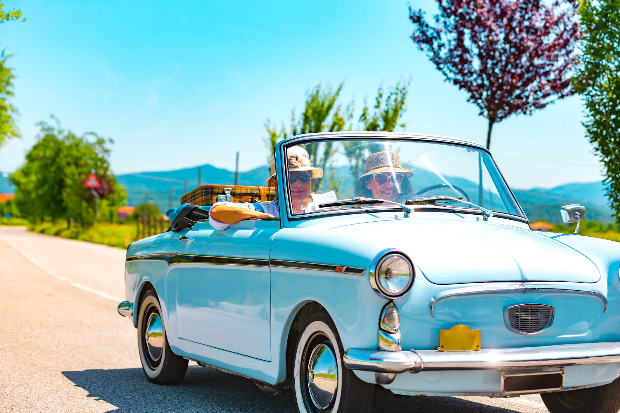 Un couple de seniors pendant un road trip à bord d'une voiture de collection bleu ciel d écapotable.