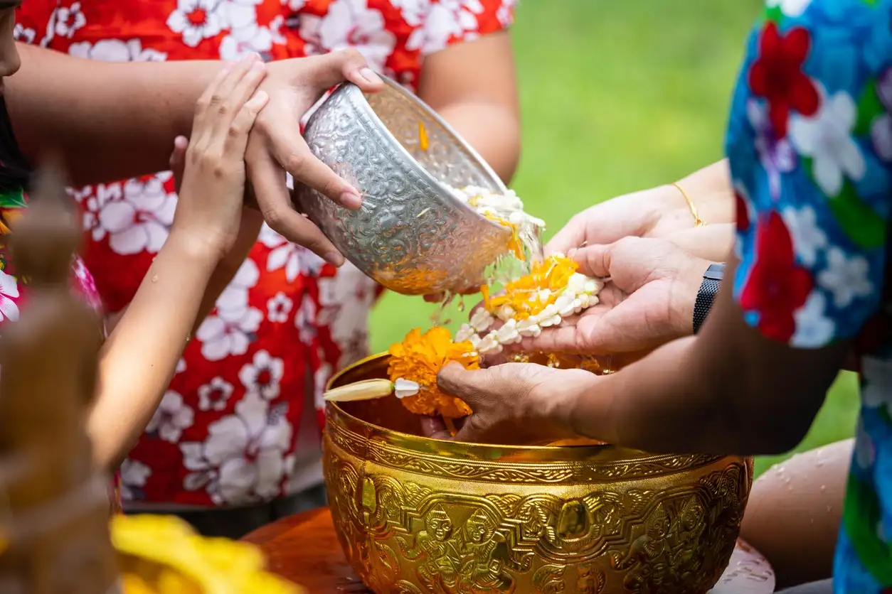 Rituel du Songkran, petite fille versant de l'eau sur les mains de personnes plus âgées