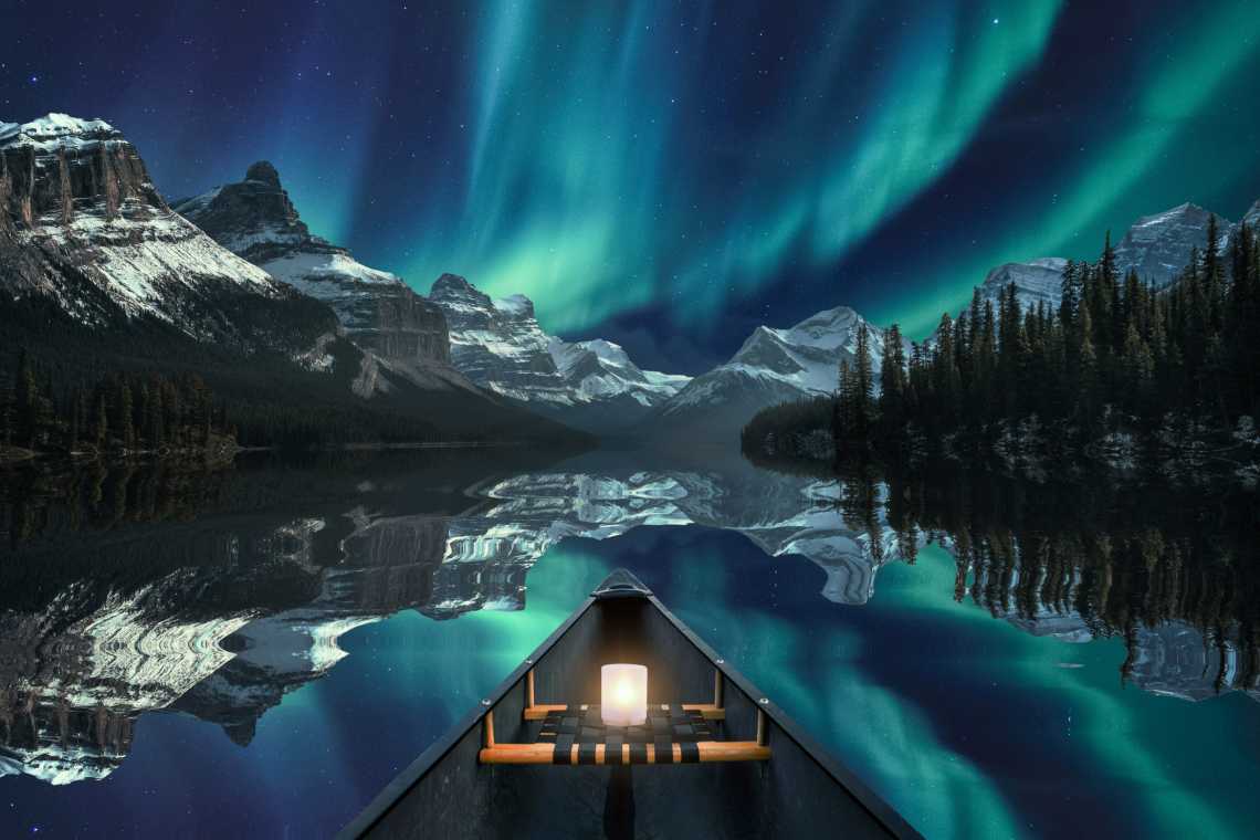 Kanufahrt mit Aurora Borealis über einer Bergkette im Maligne Lake im Jasper National Park, Kanada.