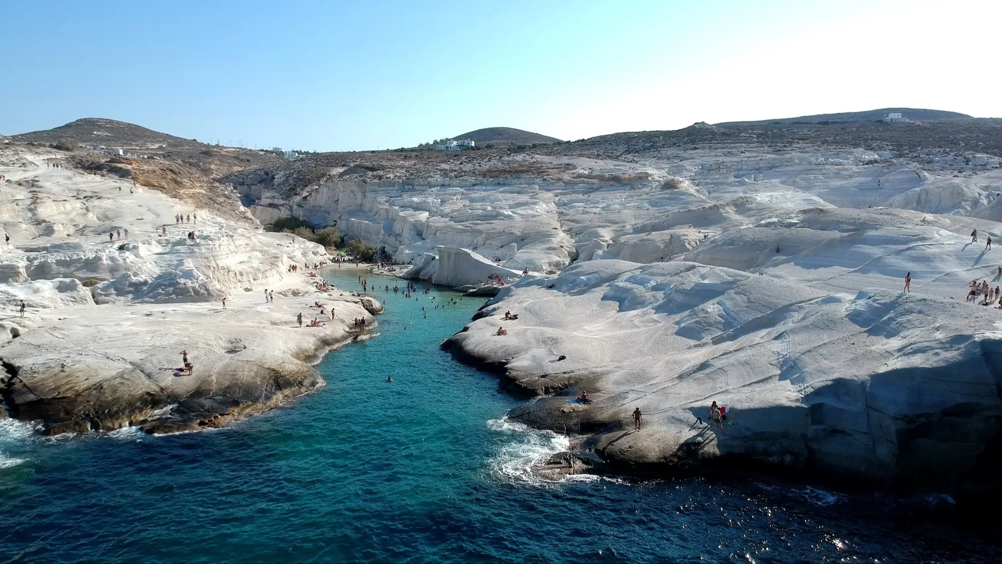 Griechenland, Kykladen, Milos, Sarakiniko Beach Luftaufnahme des Sarakiniko Beach in Milos, Kykladen, Griechenland mit Blick auf die weißen Klippen und das blaue Meer sowie Hügeln im Hintergrund.
