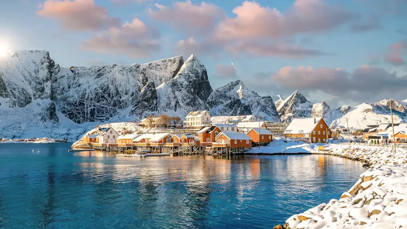 Villages côtiers enneigés avec montagnes en arrière-plan, Reine, Nordland, Norvège.