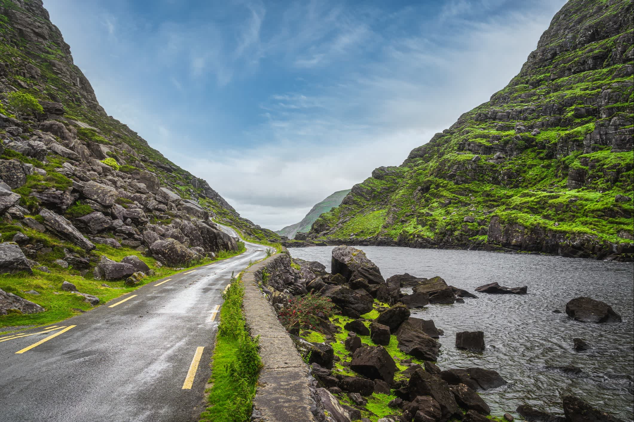 Kurvenreiche Straße entlang eines Flusses im Black Valley, Ring of Kerry, Irland.